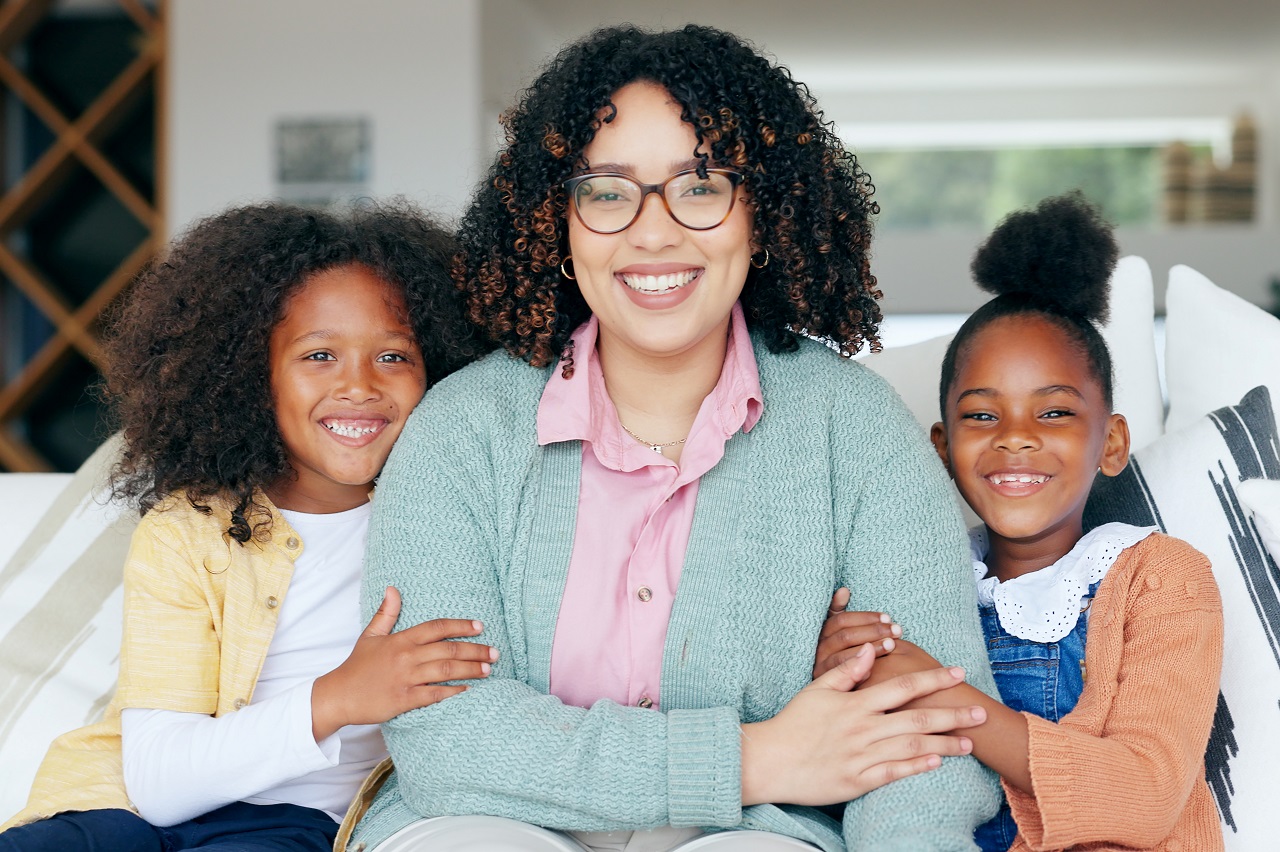 happy mom and daughters at home on sofa